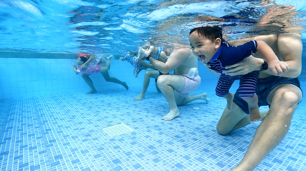babies under water in a swim class with mums and dads